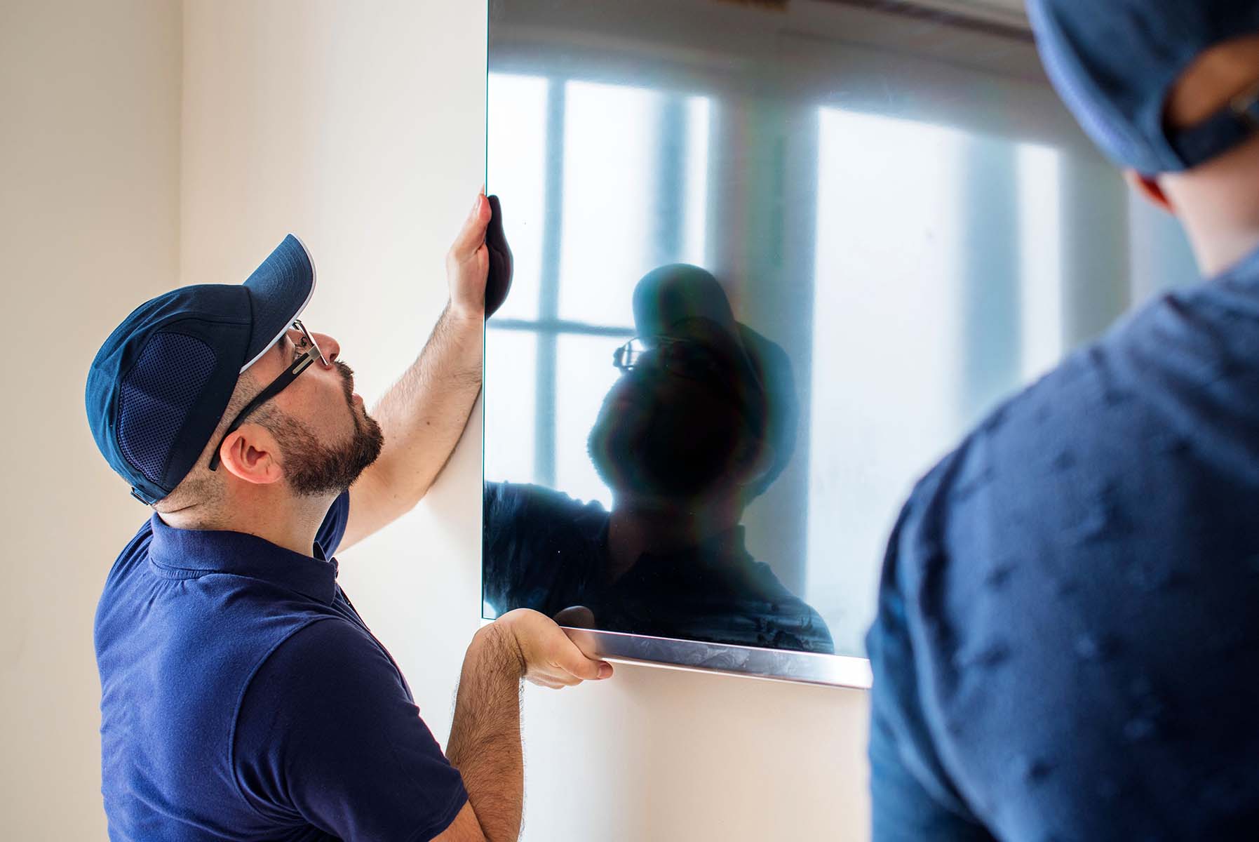 Man installing a TV on a wall.