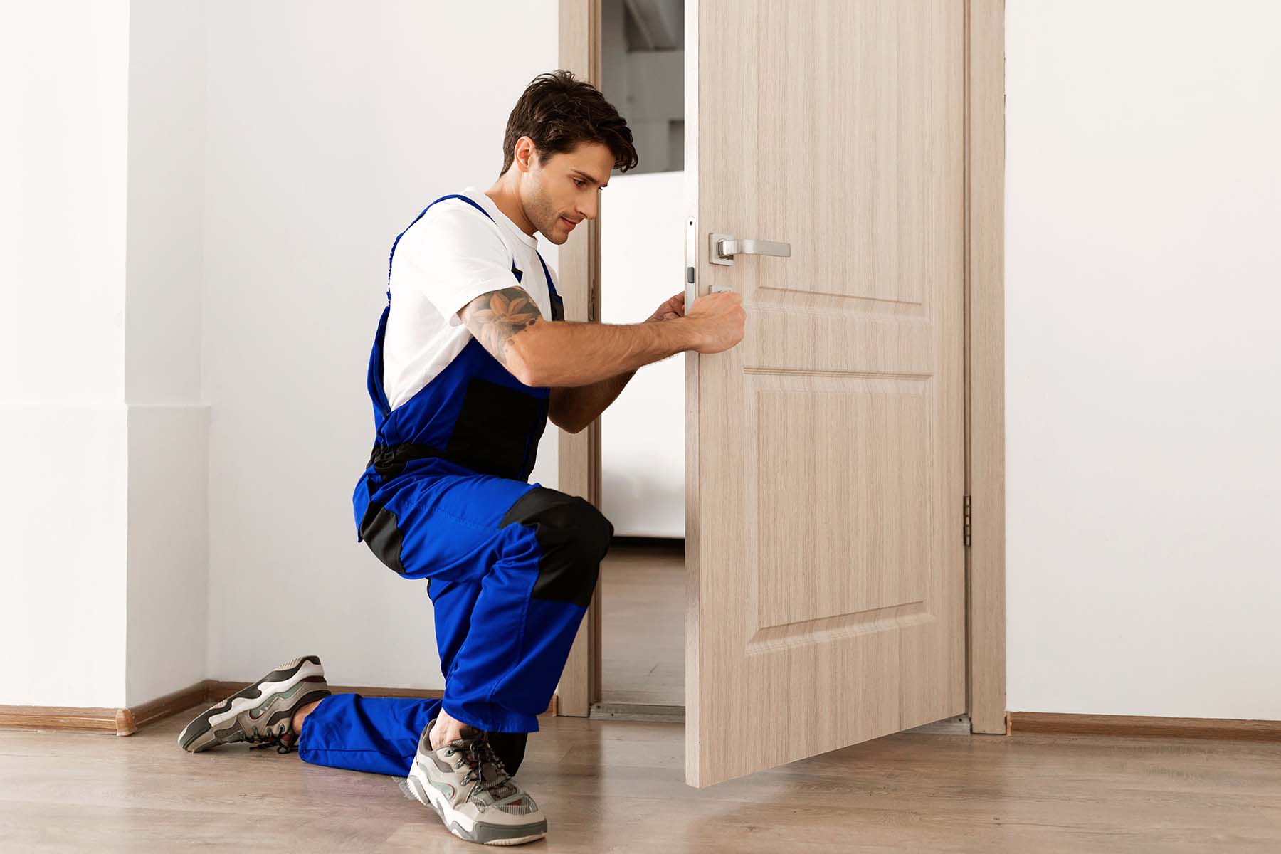 Man in workwear fixing a door handle.